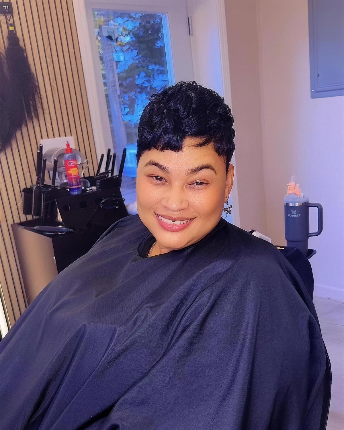 Pixie cut, smooth and shaped, client smiling in the chair.